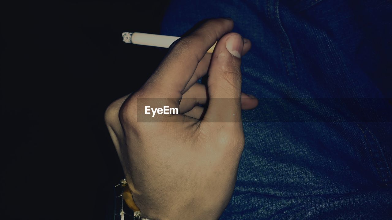 Cropped image of person holding cigarette