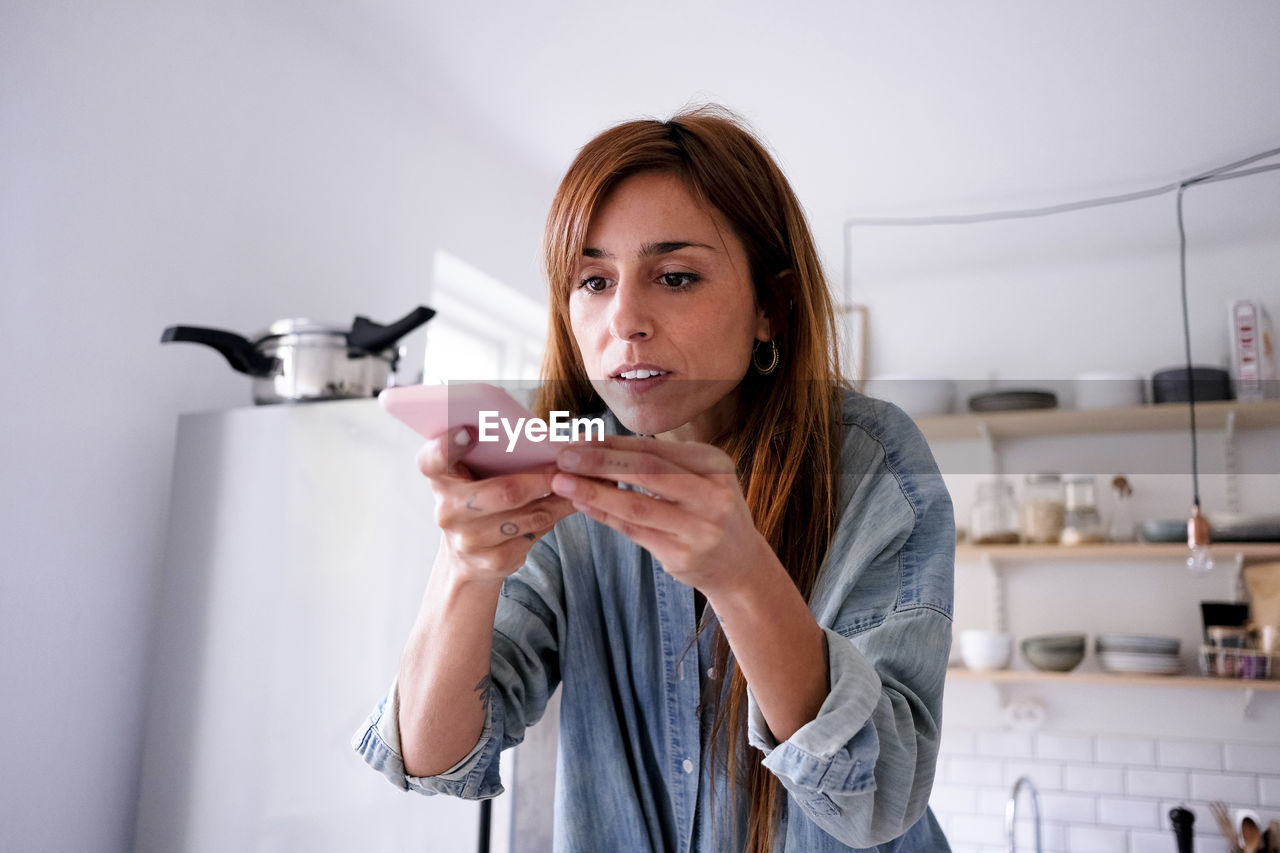 Blogger photographing through mobile phone at home