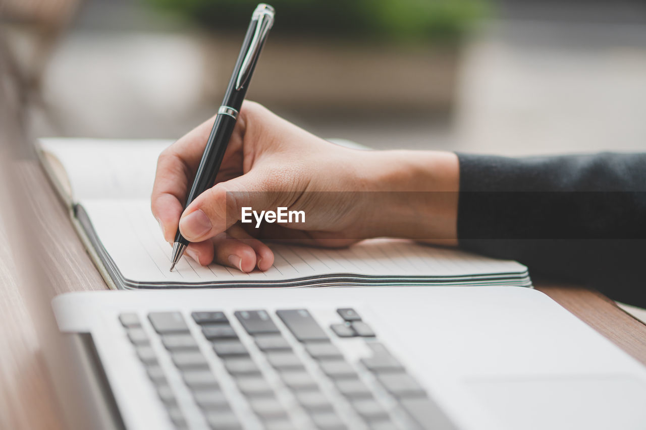 cropped hands of woman using laptop at table