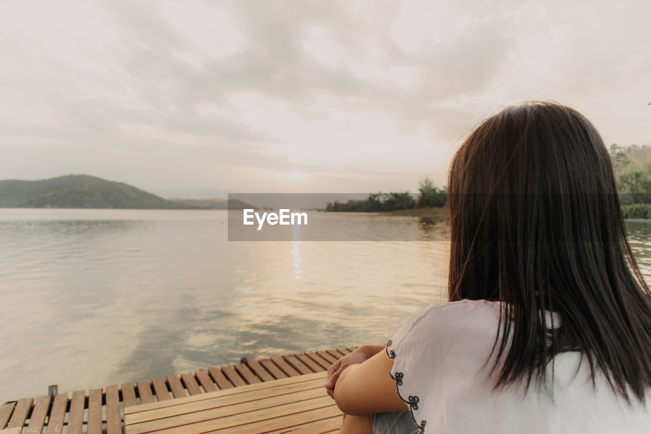 REAR VIEW OF WOMAN LOOKING AT VIEW OF SEA