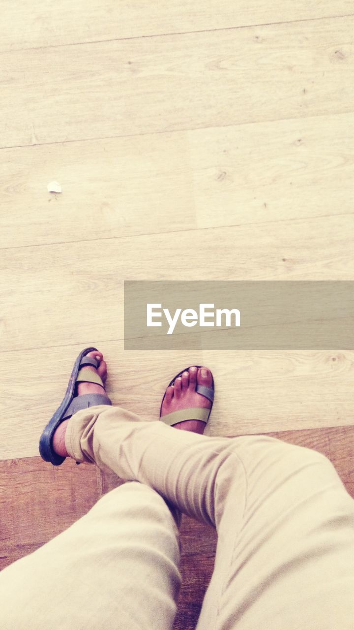 Low section of man standing on hardwood floor