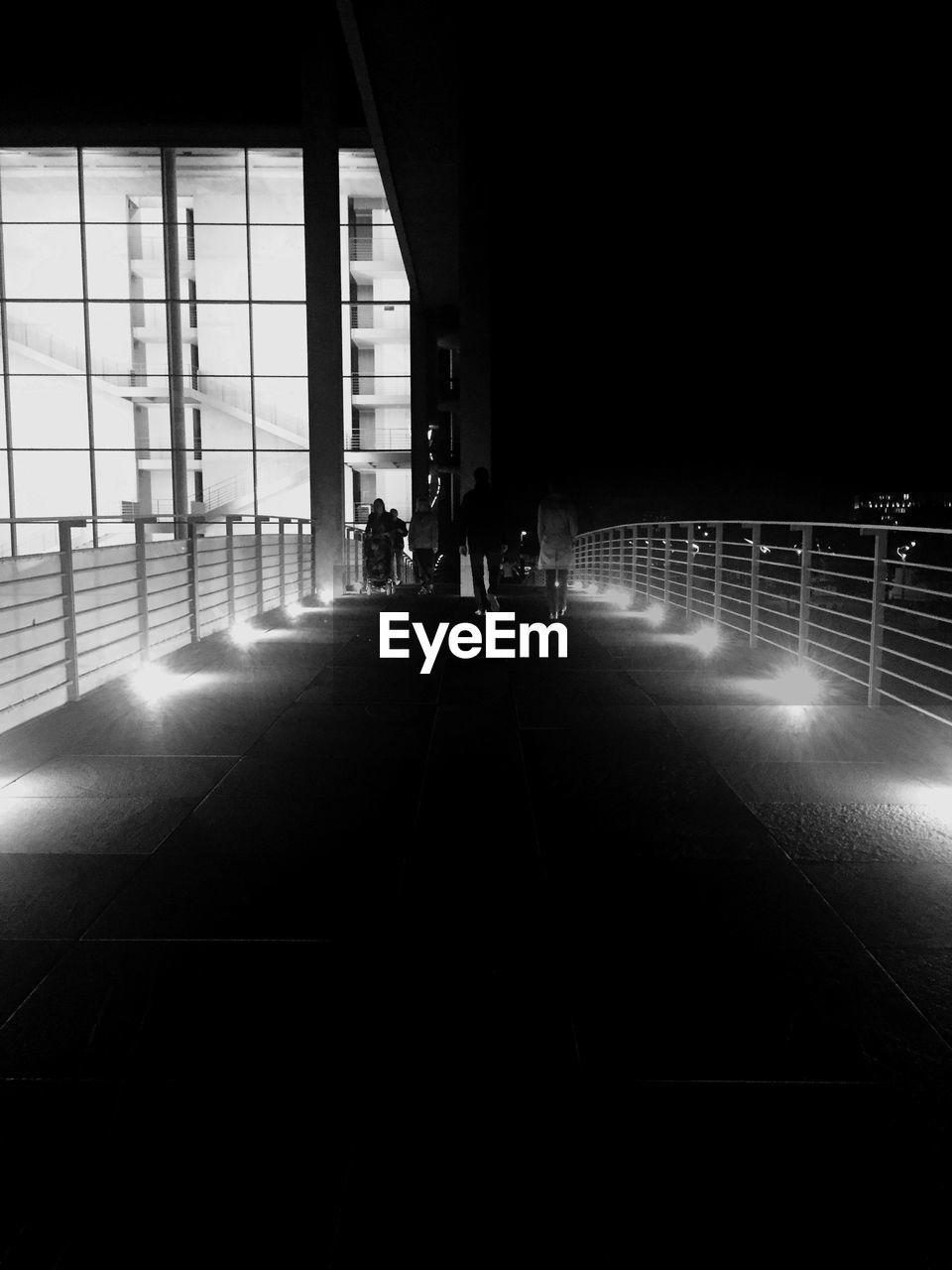 People on bridge against sky at night