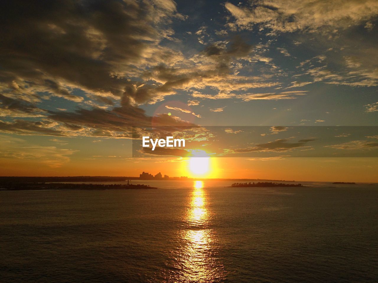 Scenic view of sea against cloudy sky during sunset