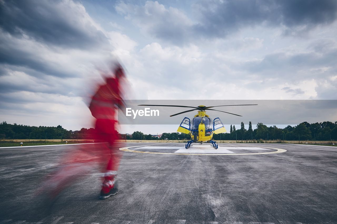 Ground crew running on airport runway against helicopter