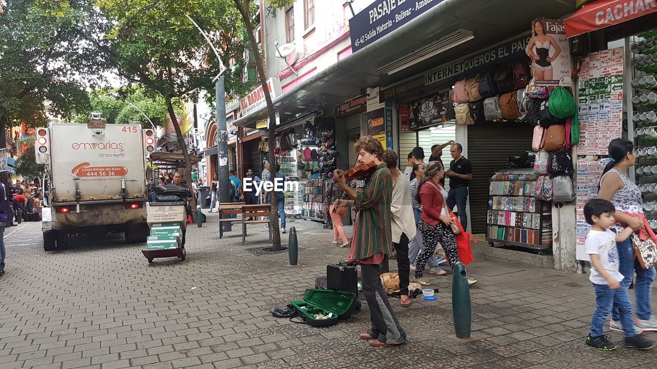 PEOPLE ON STREET AGAINST BUILDINGS IN CITY