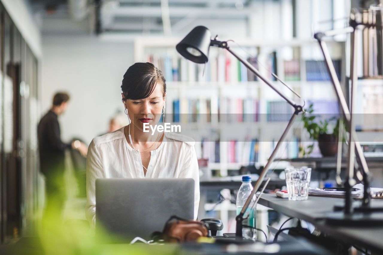 Creative businesswoman using laptop at desk in office