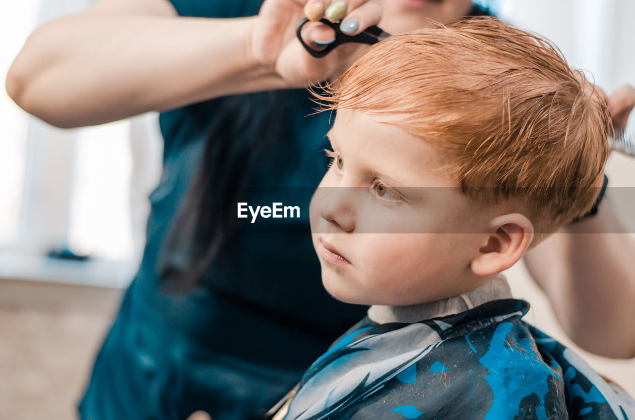 4 year old redhead boy at the barbershop. hairdresser cuts a child's hair