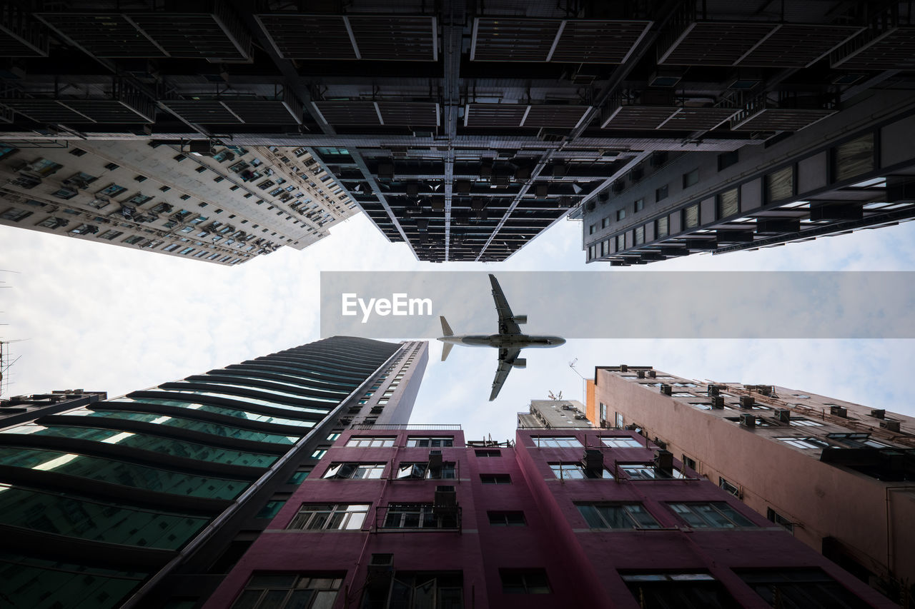 Airplane flying over buildings against sky