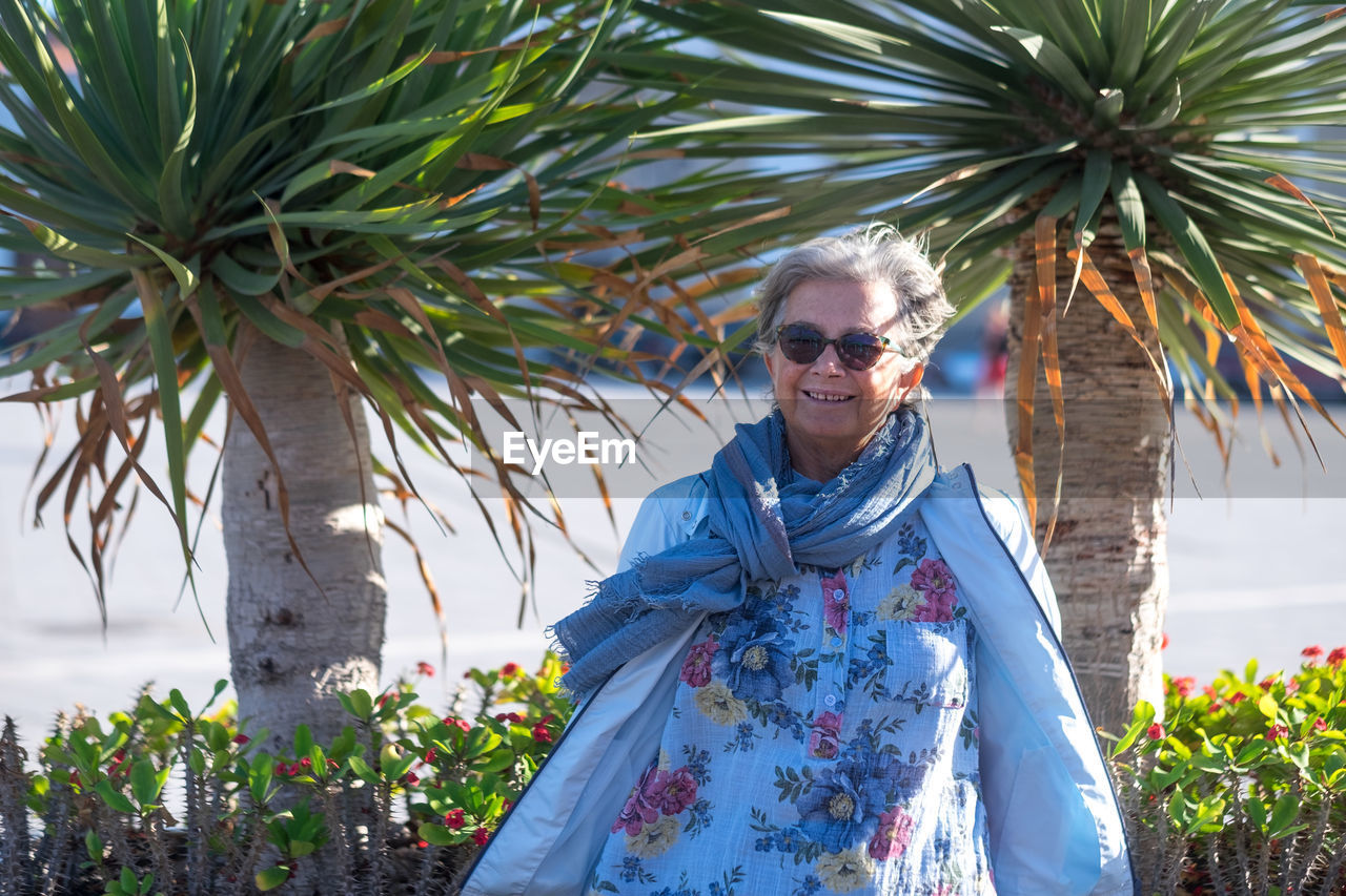 Portrait of senior woman standing against trees