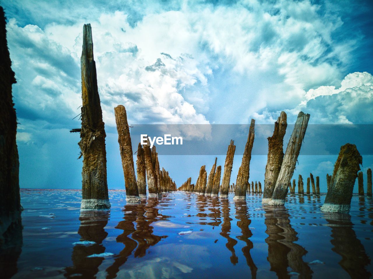 Panoramic view of wooden posts on water against sky