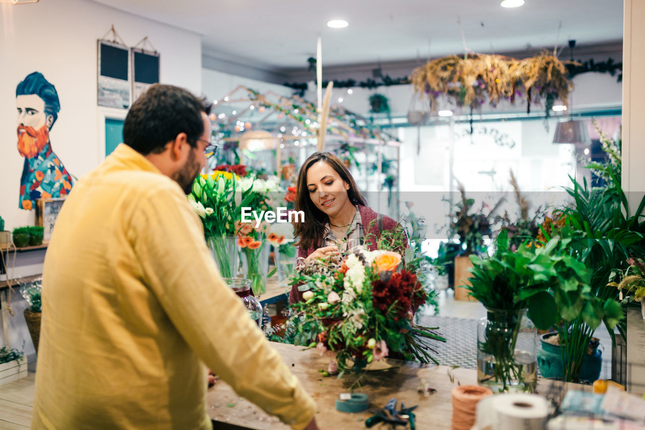 Rear view of man with woman holding bouquet at store