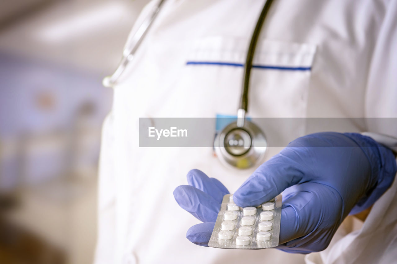 Midsection of doctor holding pills in hospital