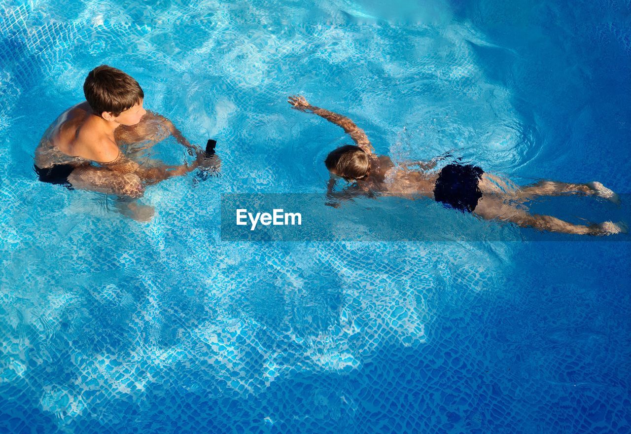 Two boys in the pool with an action camera