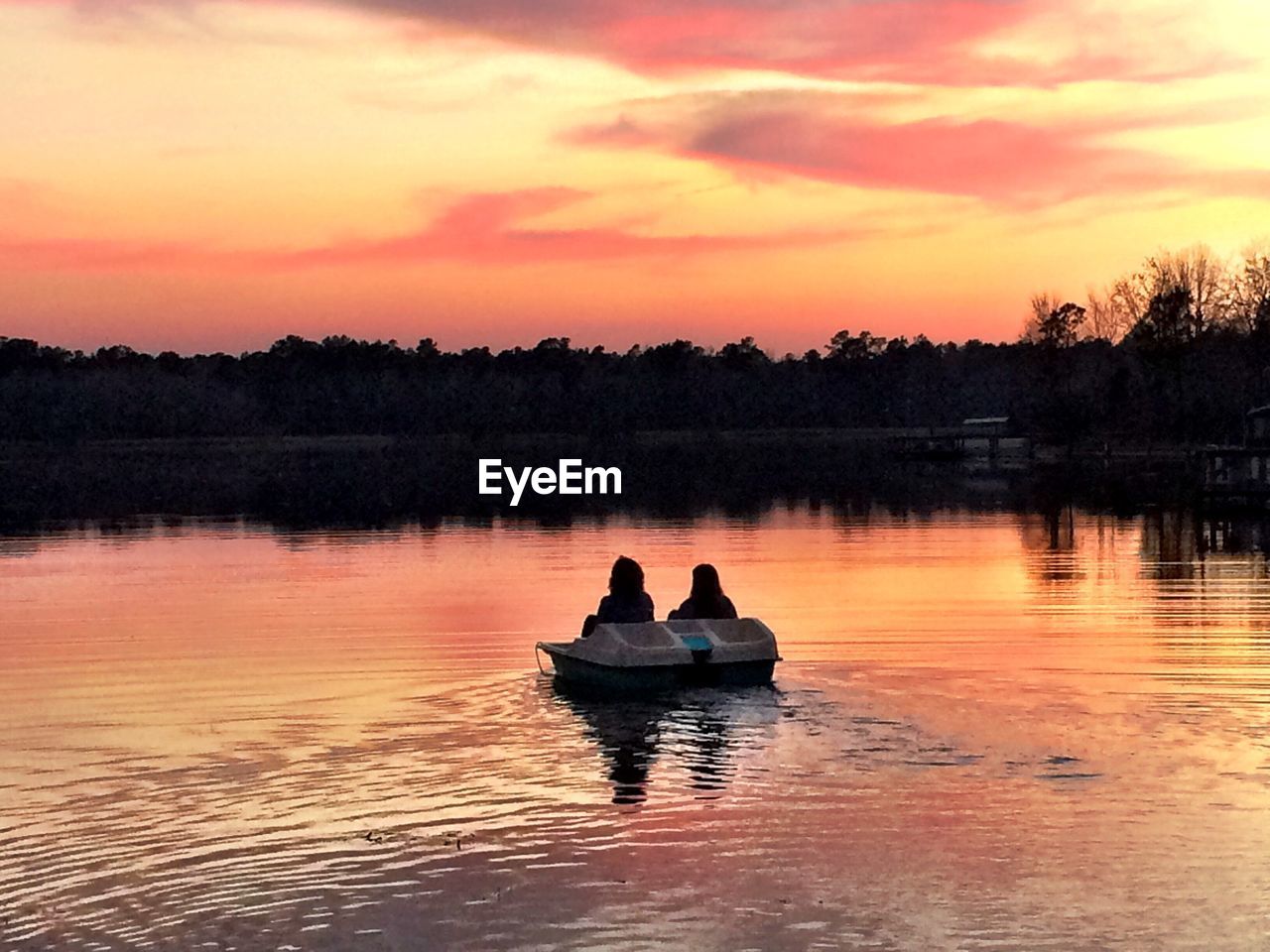 Boat in calm lake at sunset