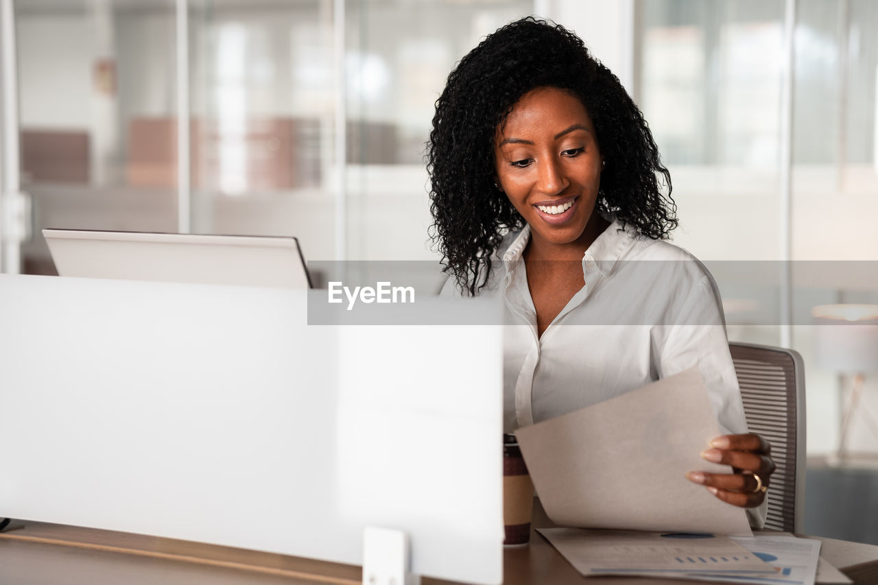 PORTRAIT OF A SMILING YOUNG WOMAN USING LAPTOP