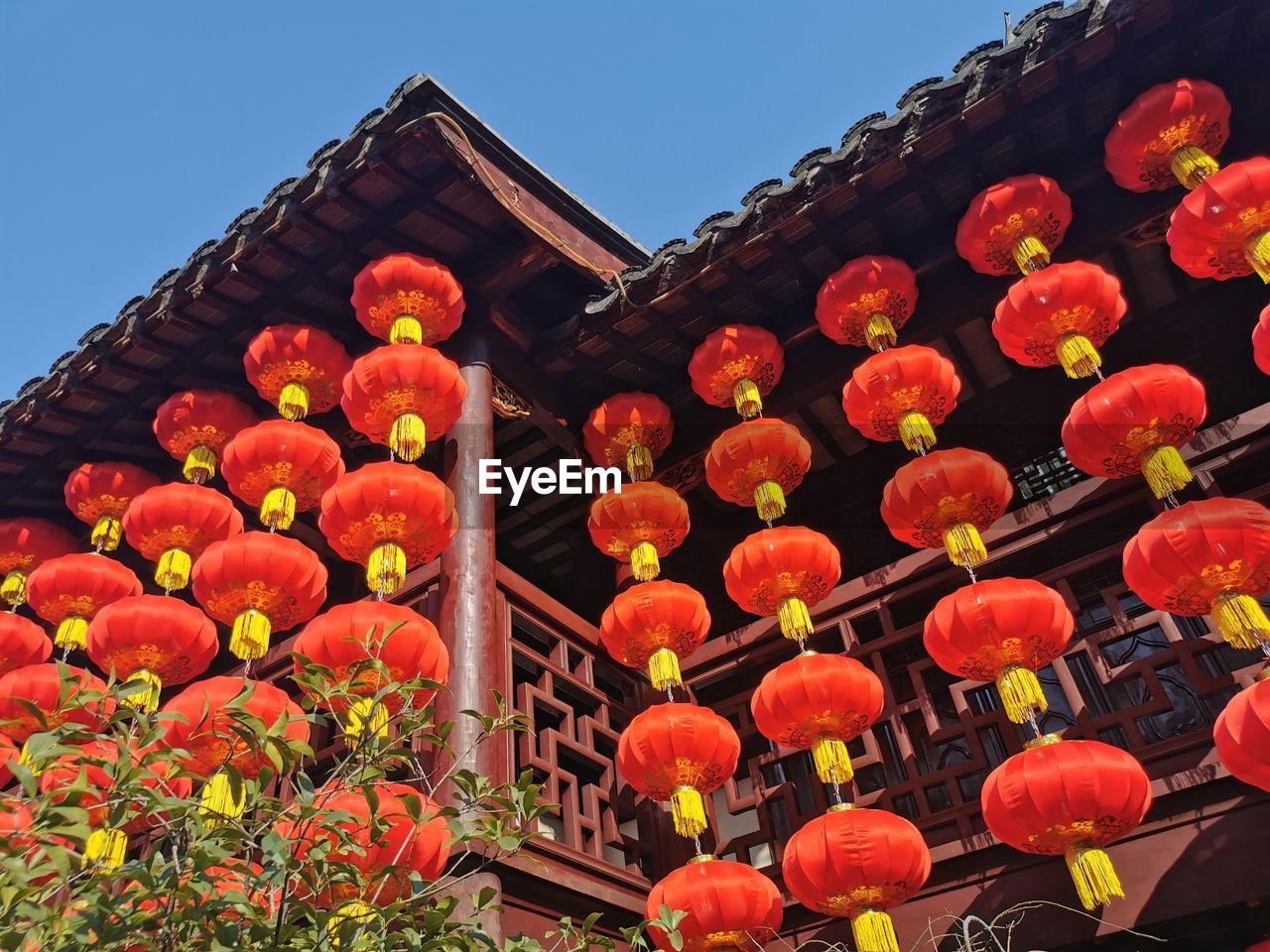 LOW ANGLE VIEW OF RED LANTERNS AGAINST BUILDING