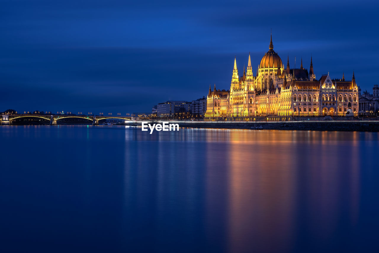 ILLUMINATED CITY BUILDINGS AT WATERFRONT