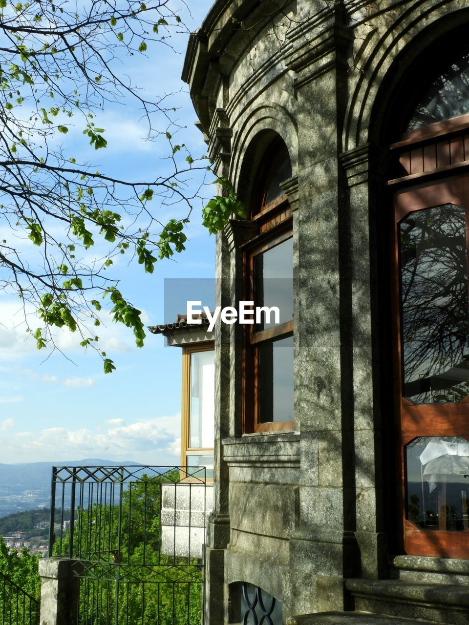 LOW ANGLE VIEW OF BUILDING BY TREES AGAINST SKY