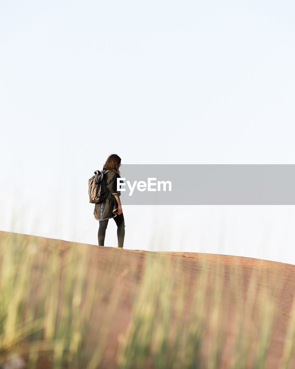 Woman walking on desert against clear sky