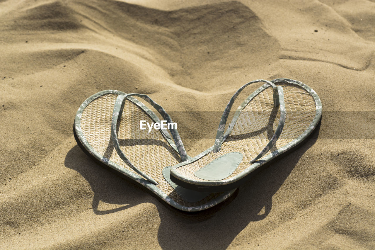 High angle view of flip-flops on sand at beach