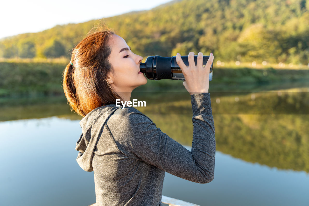 Young attractive and active woman drinking water from her plastic water bottle while taking a break