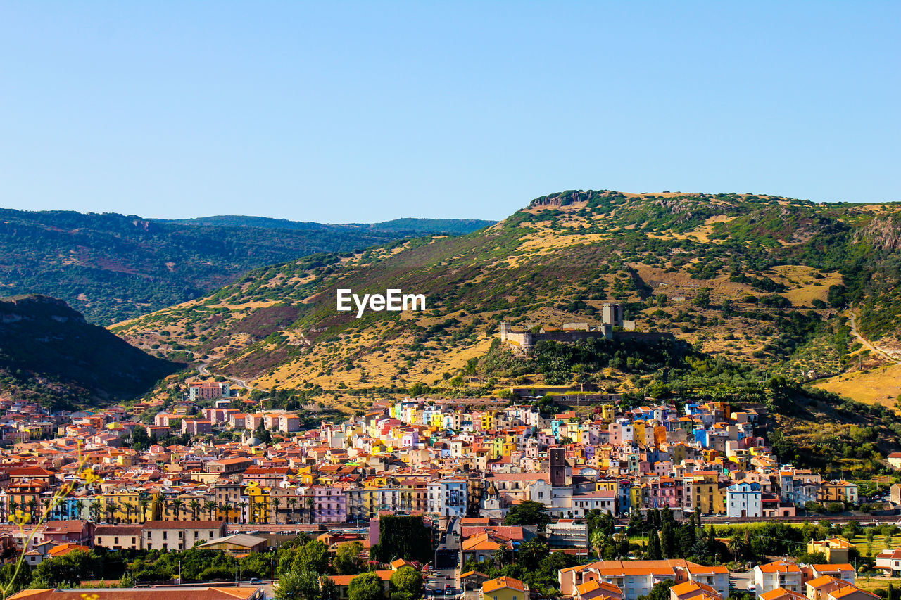 AERIAL VIEW OF TOWNSCAPE AGAINST MOUNTAIN