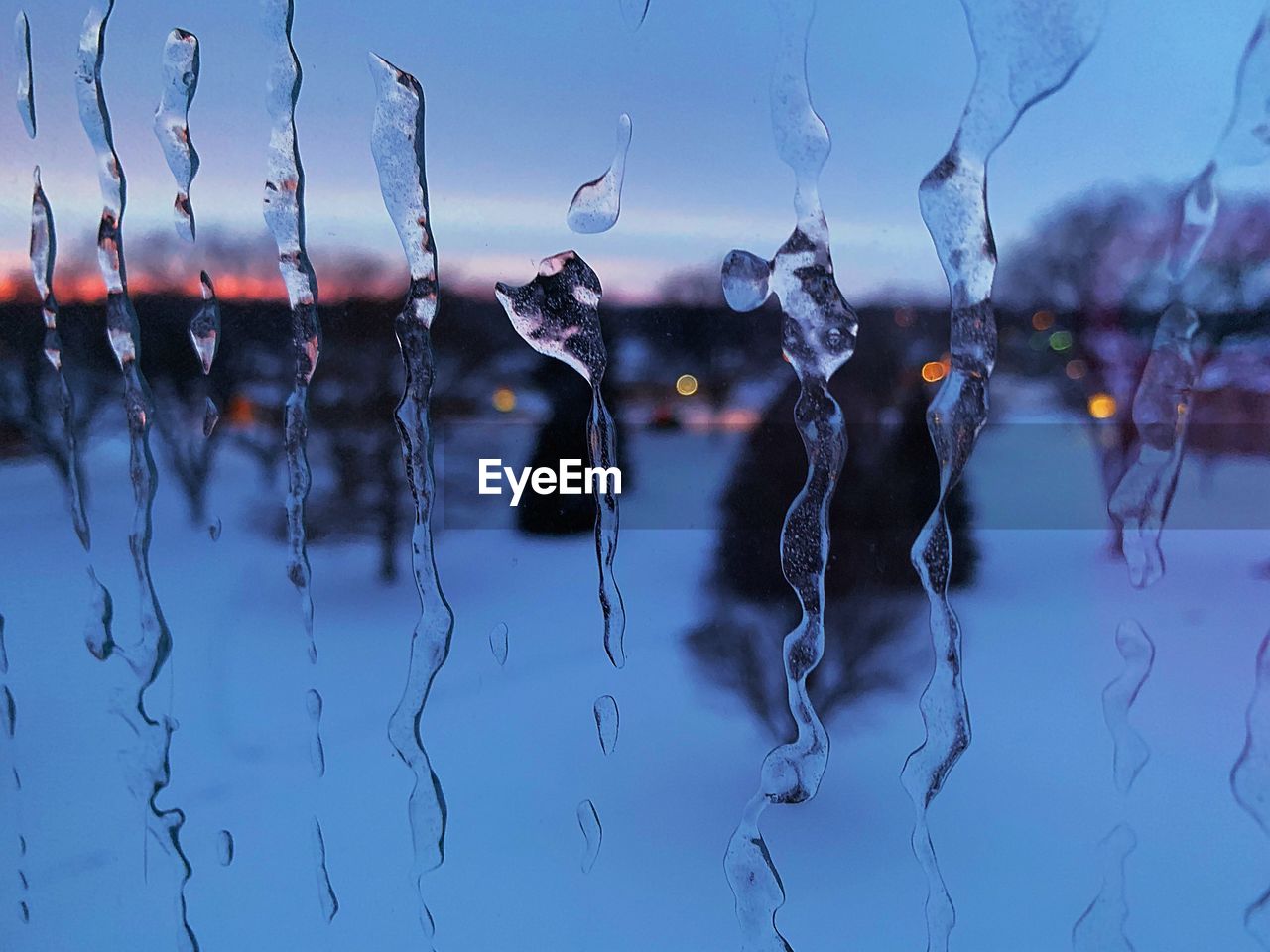 Close-up of raindrops on window against sky