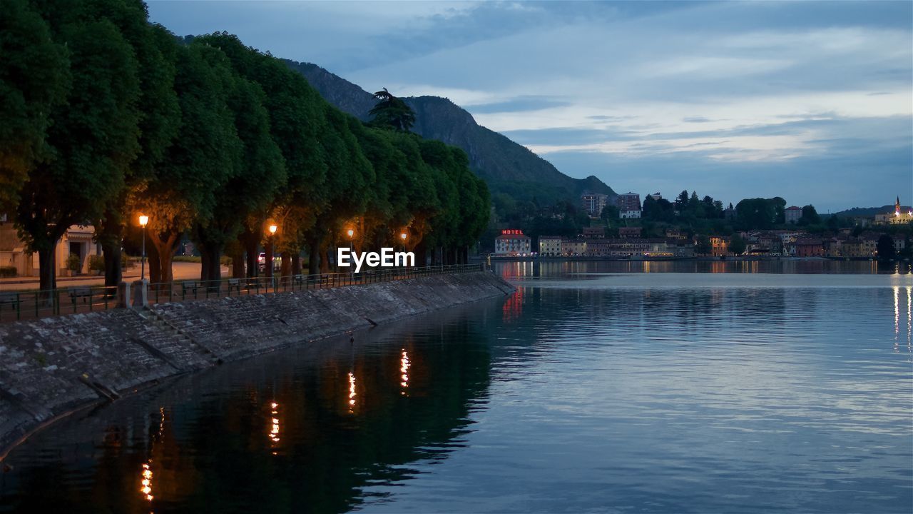 ILLUMINATED BUILDING BY LAKE AGAINST SKY AT DUSK