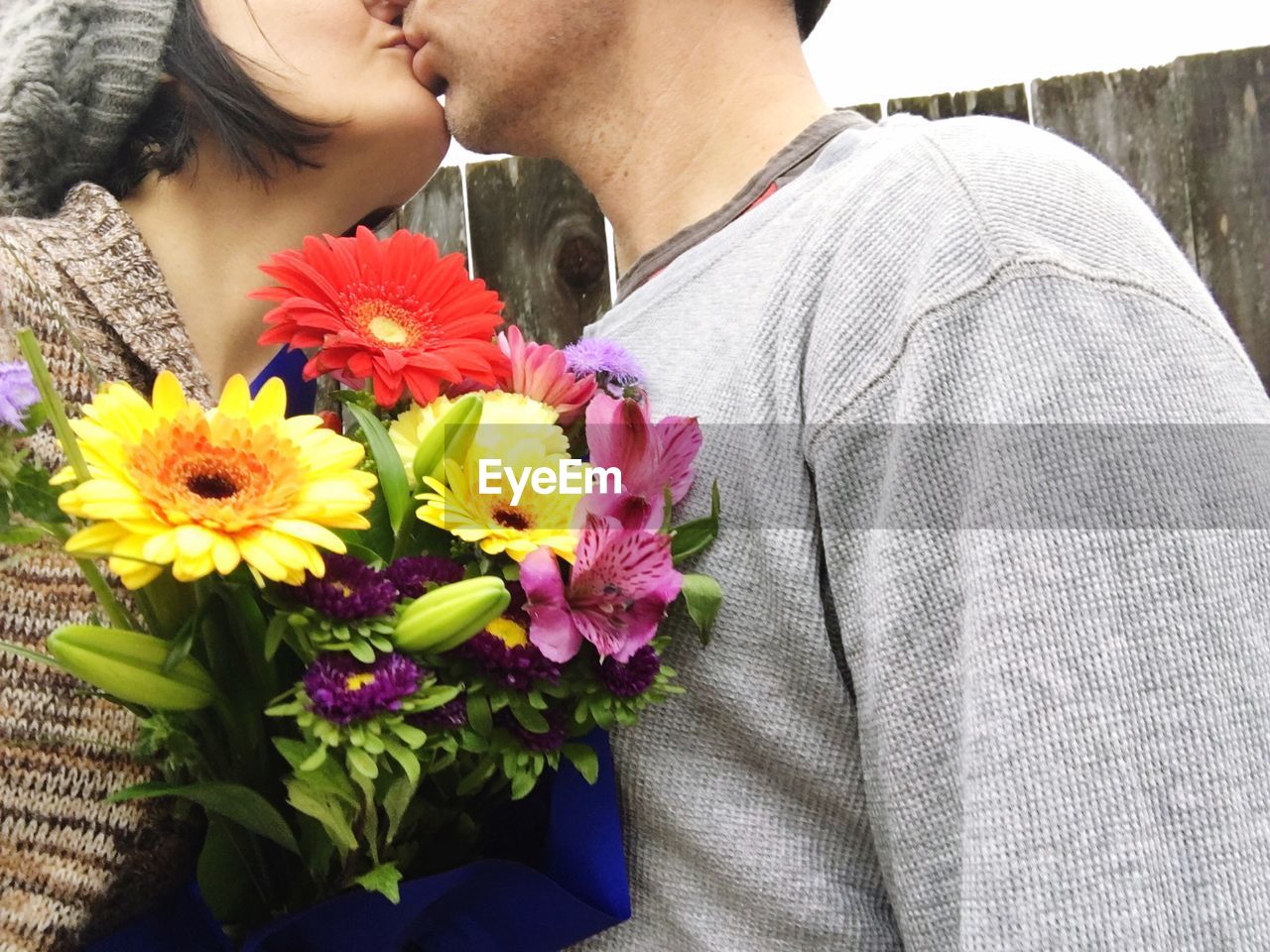Couple kissing while holding flower bouquet