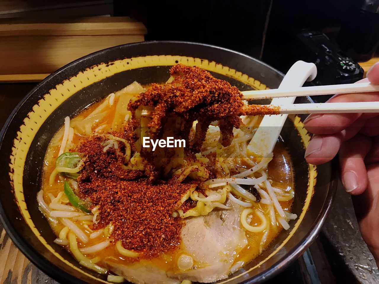 Cropped hand having noodles in bowl at table