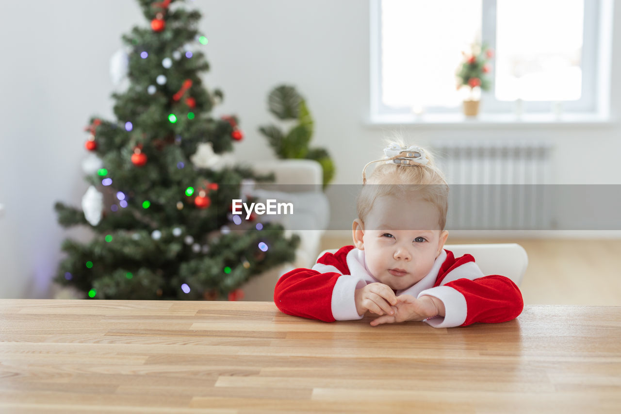 portrait of cute girl playing with christmas tree at home