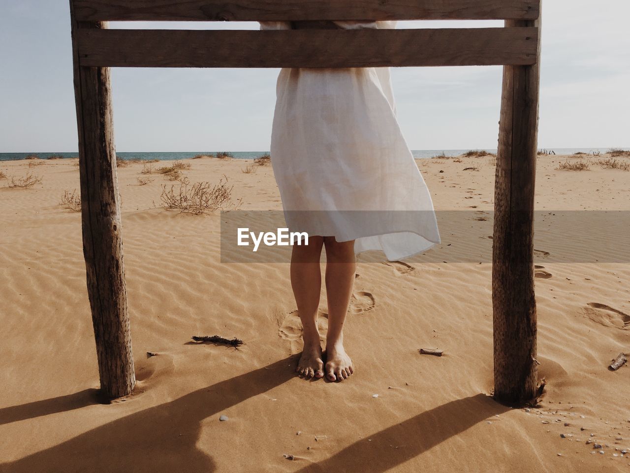 LOW SECTION OF WOMAN STANDING ON SANDY BEACH