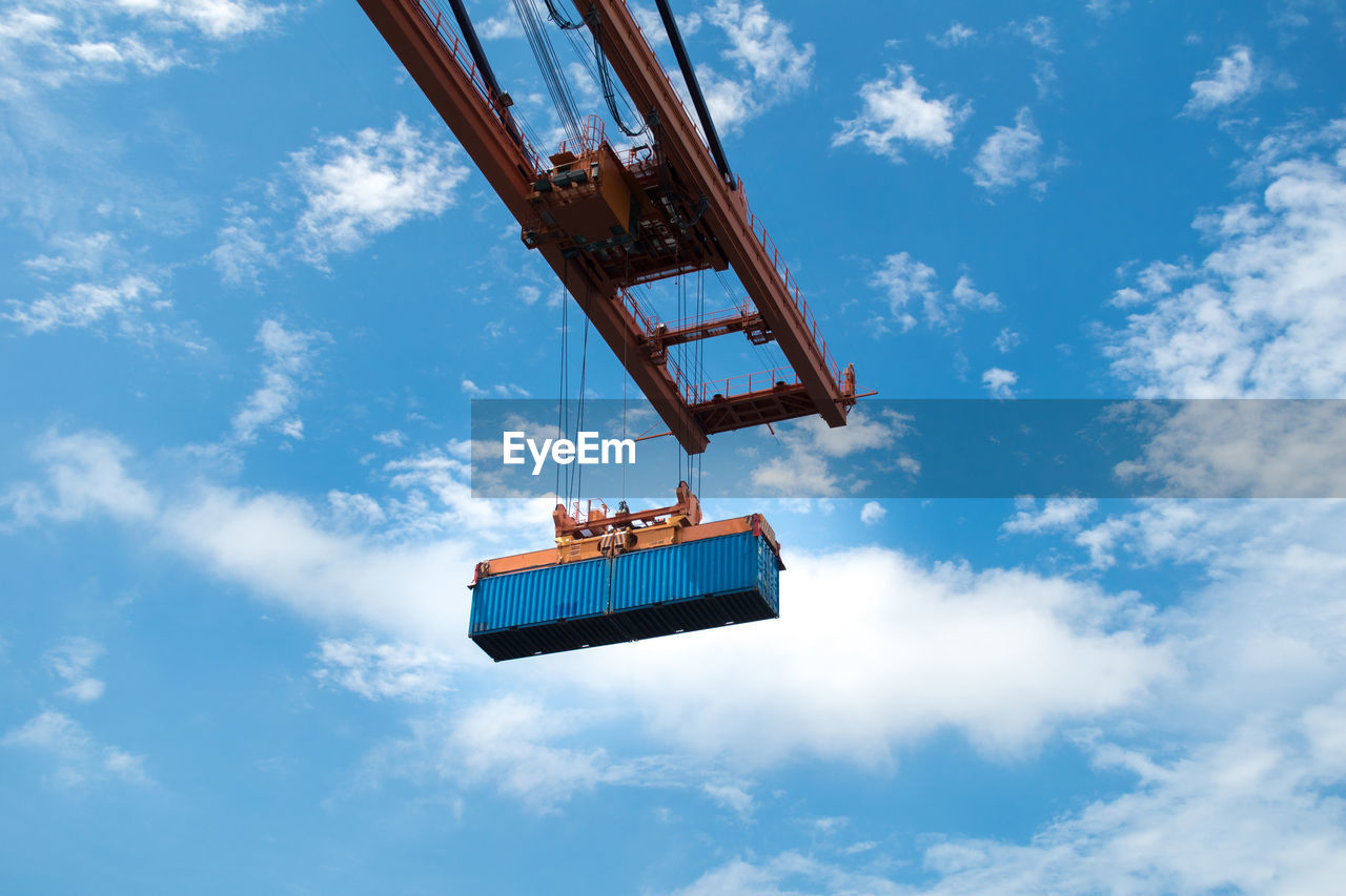 Low angle view container pick up by quantry crane against sky.