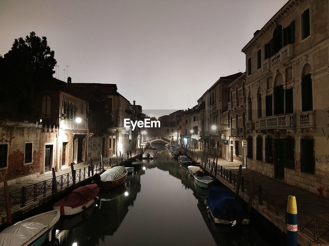 CANAL AMIDST ILLUMINATED BUILDINGS IN CITY AT NIGHT