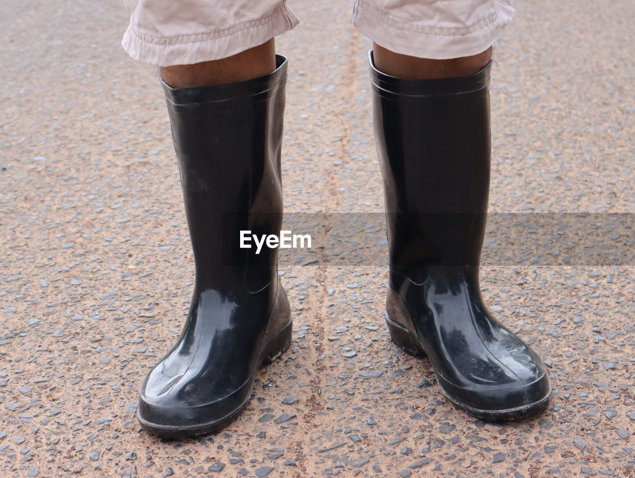 Low section of woman wearing rubber boot standing on road