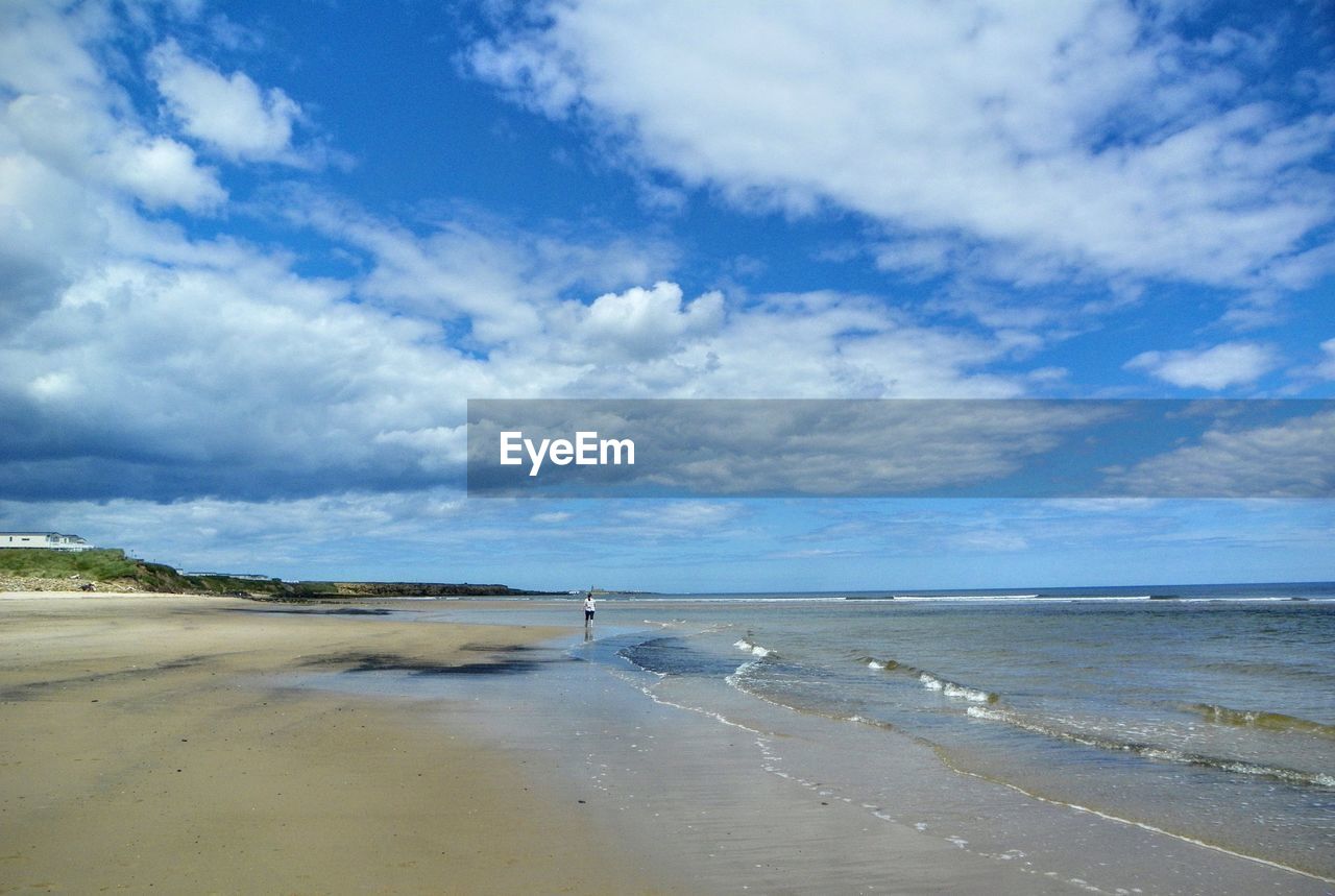 Scenic view of beach against cloudy sky