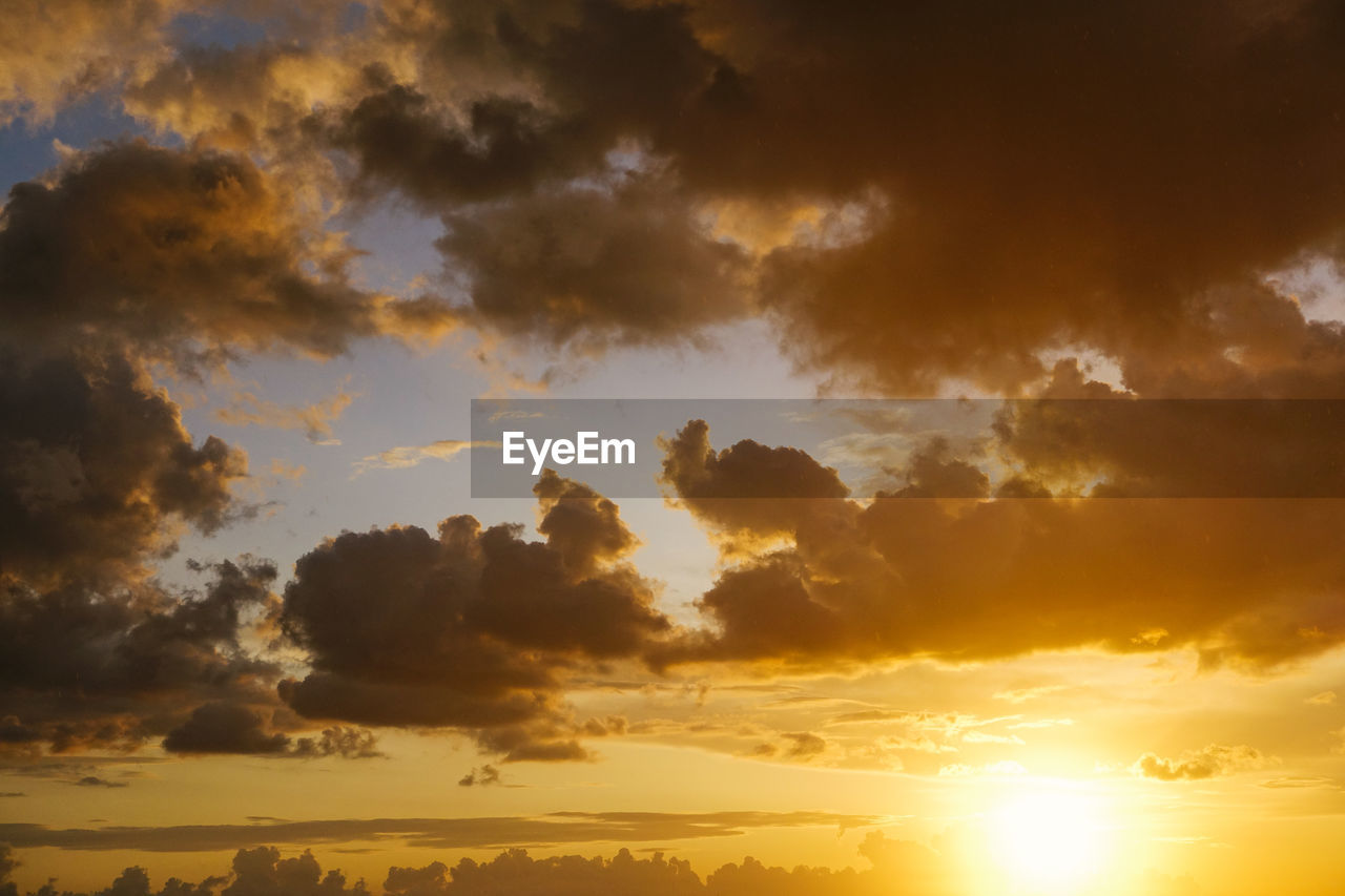 Low angle view of sun and clouds against sky during sunset