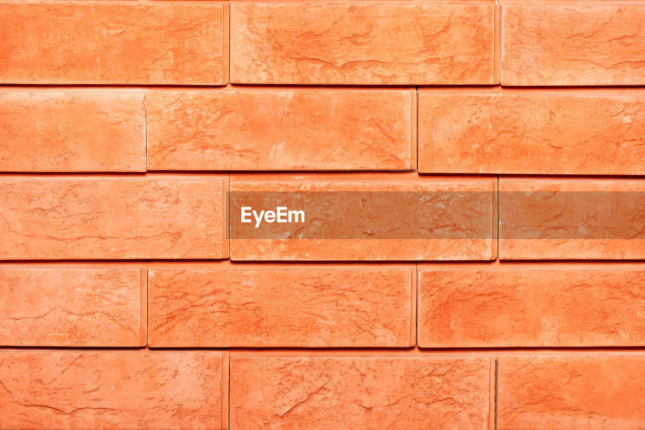 Texture of orange brick tiles on the facade of the wall close-up.