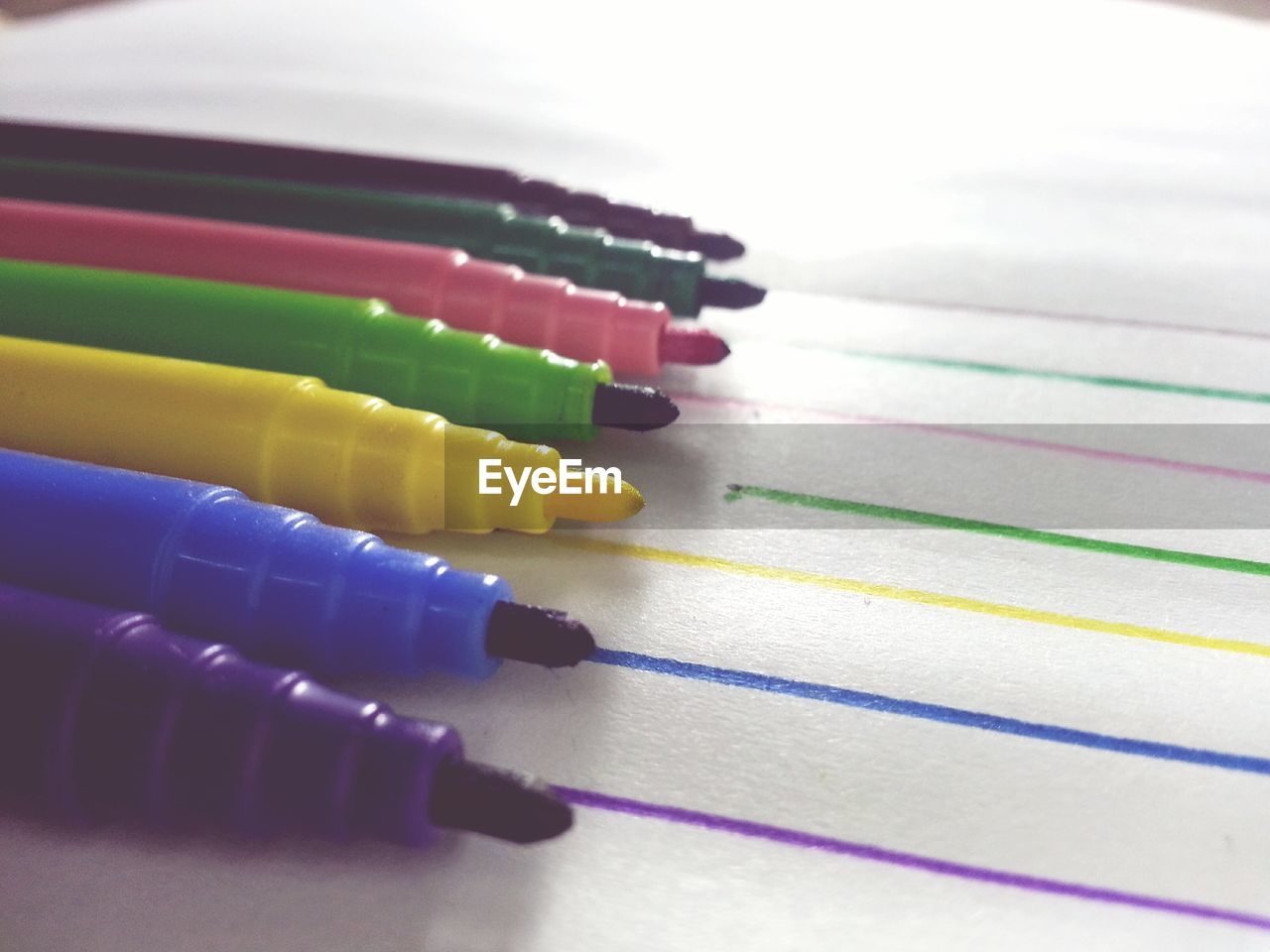 Close-up of multi colored sketch pencils in white background .