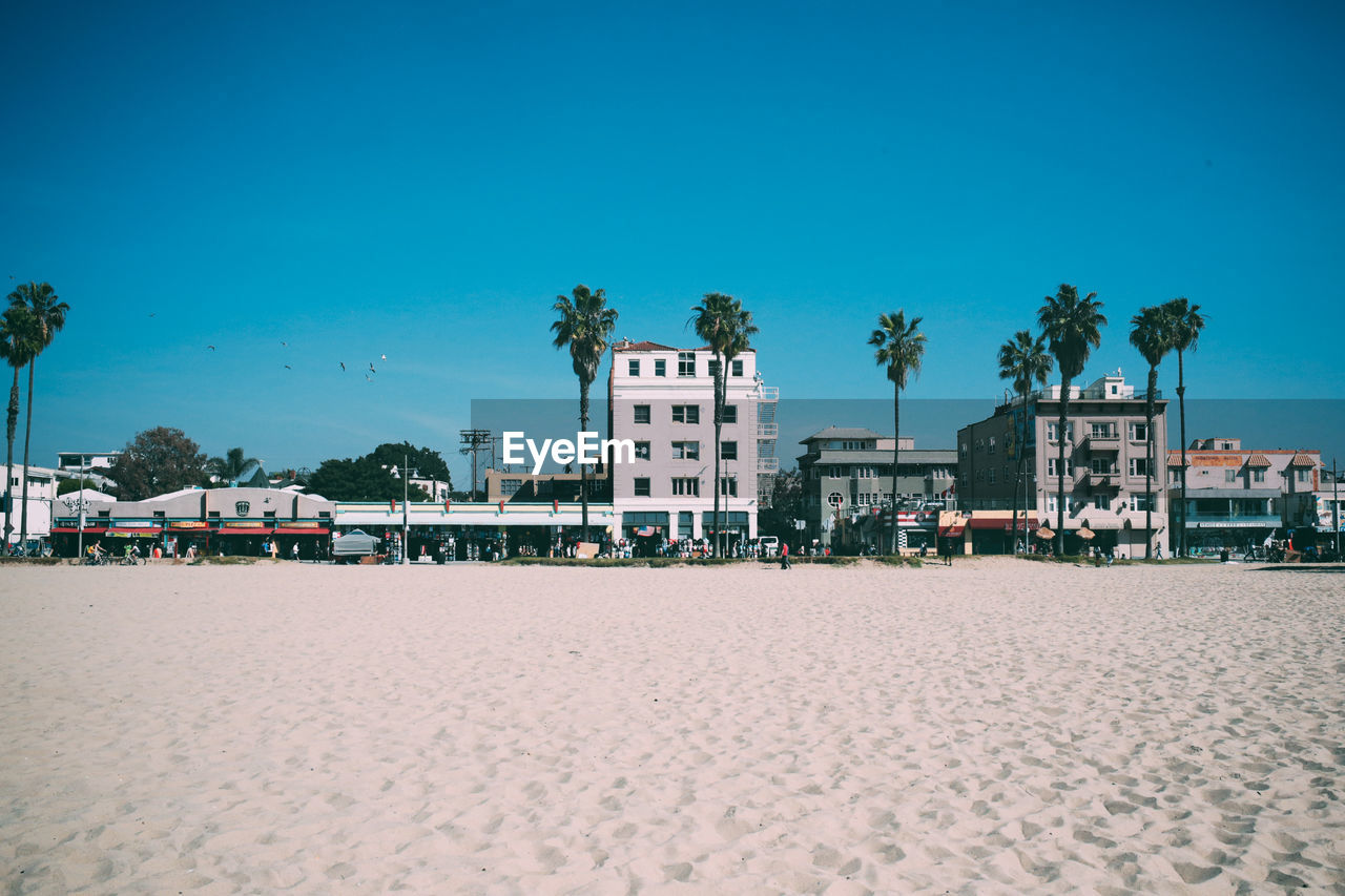 Beach against buildings in city against blue sky