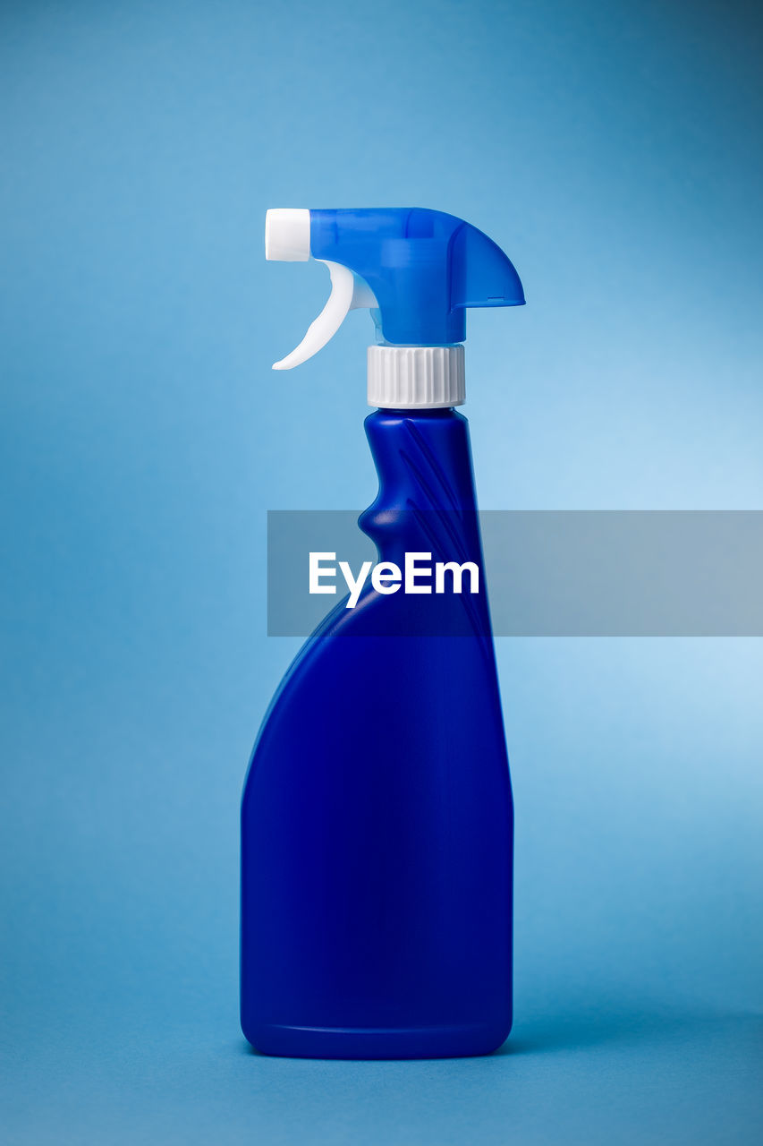 Close-up of spray bottle against blue background