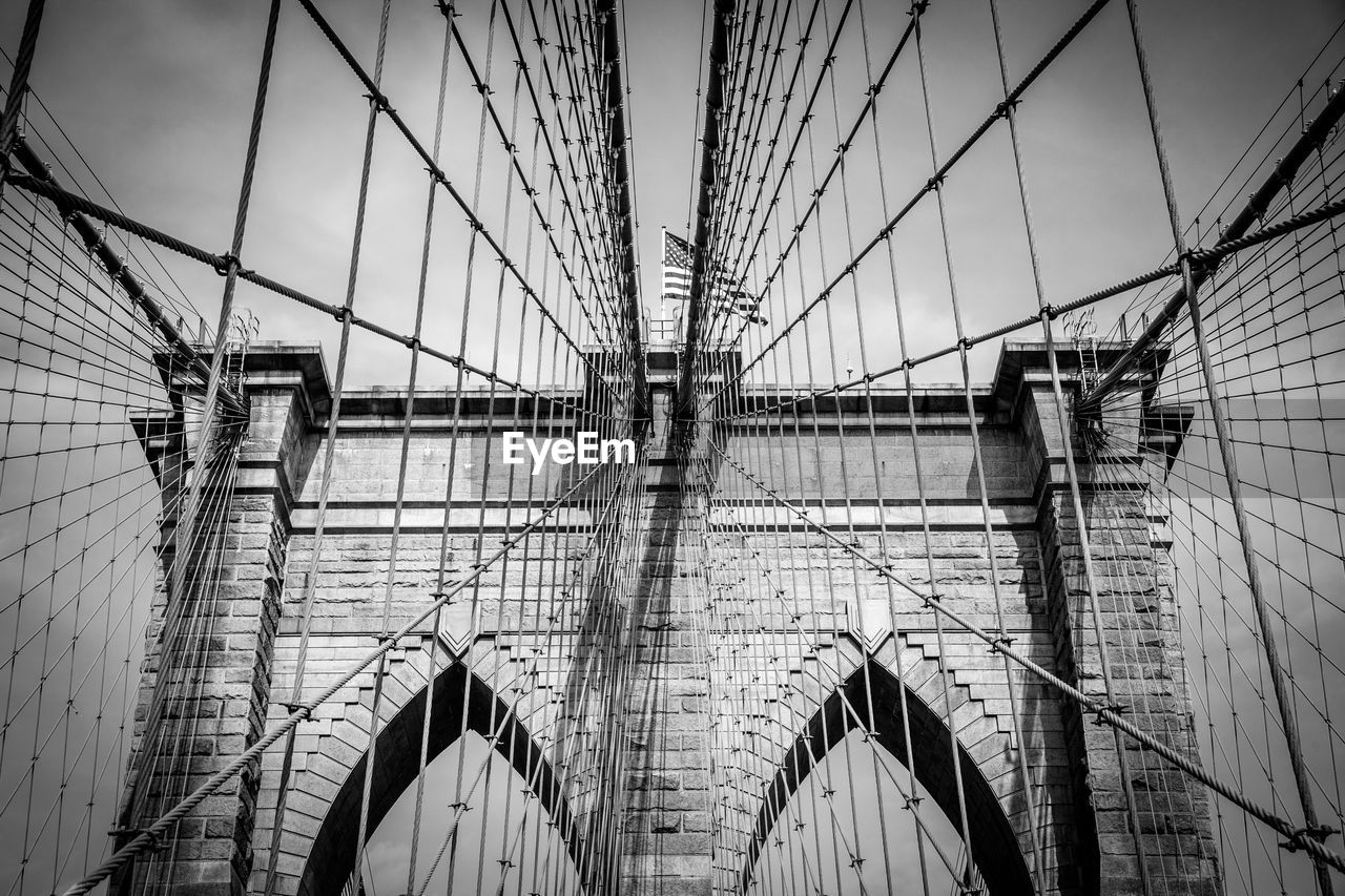 LOW ANGLE VIEW OF SUSPENSION BRIDGE AGAINST CLOUDY SKY