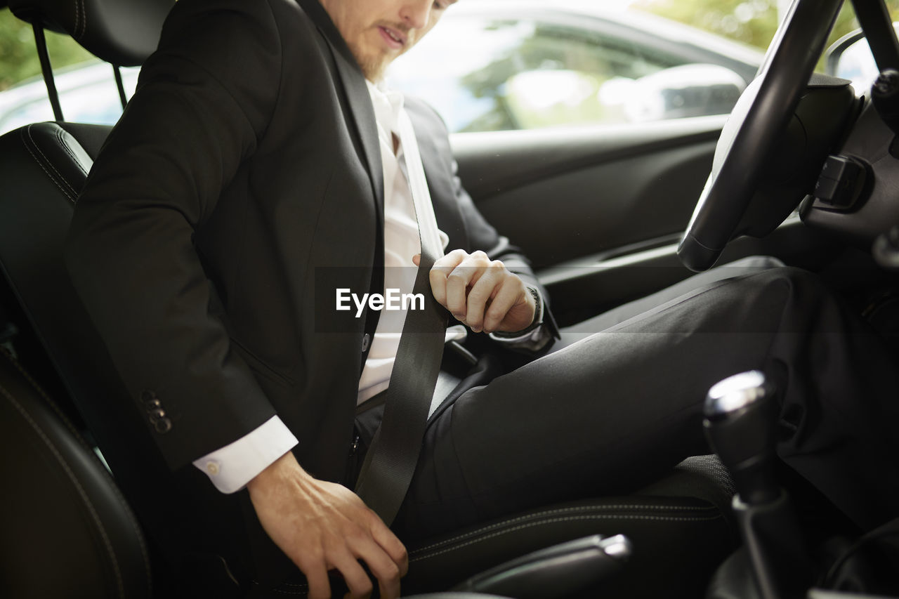 Man fastening seat belt in car