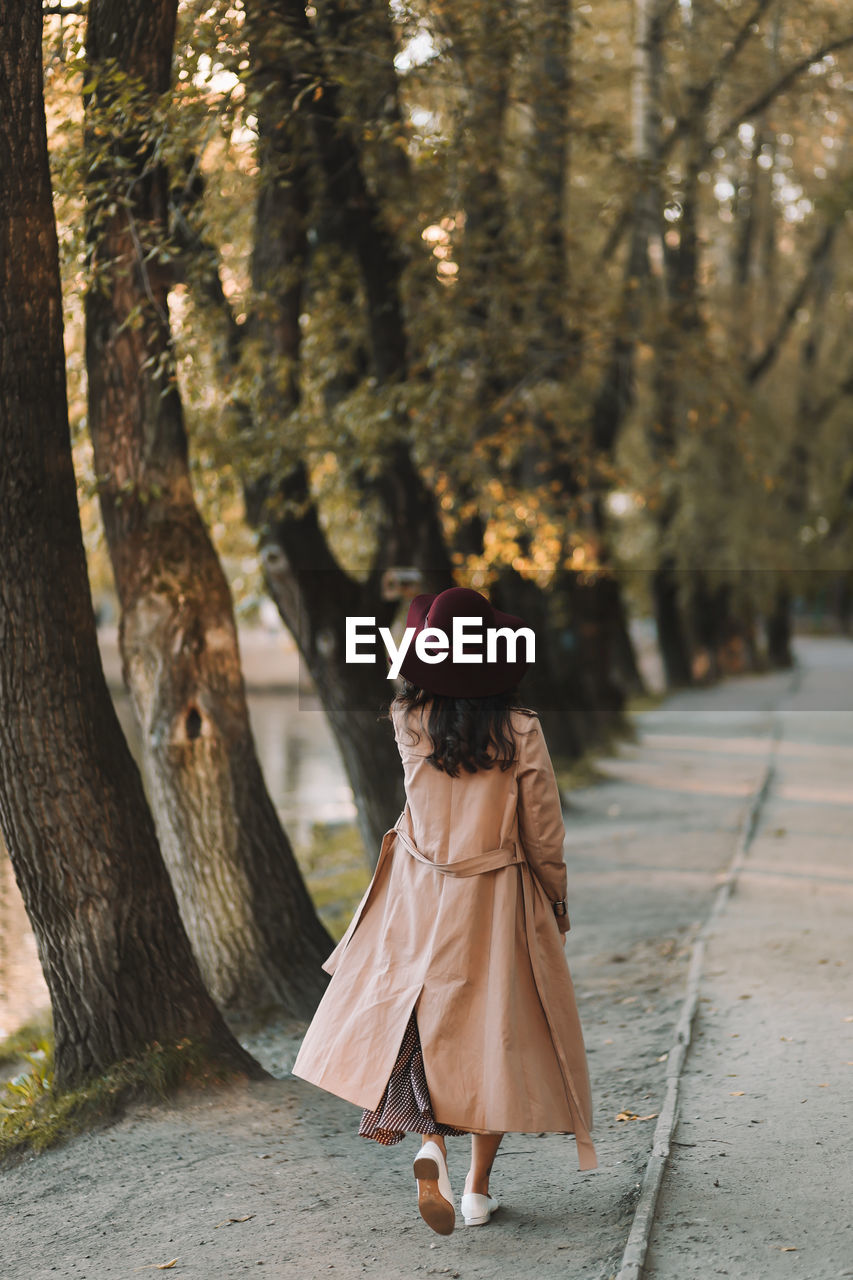 A happy single woman in elegant clothes walks in an fall park and in the forest in autumn outdoors