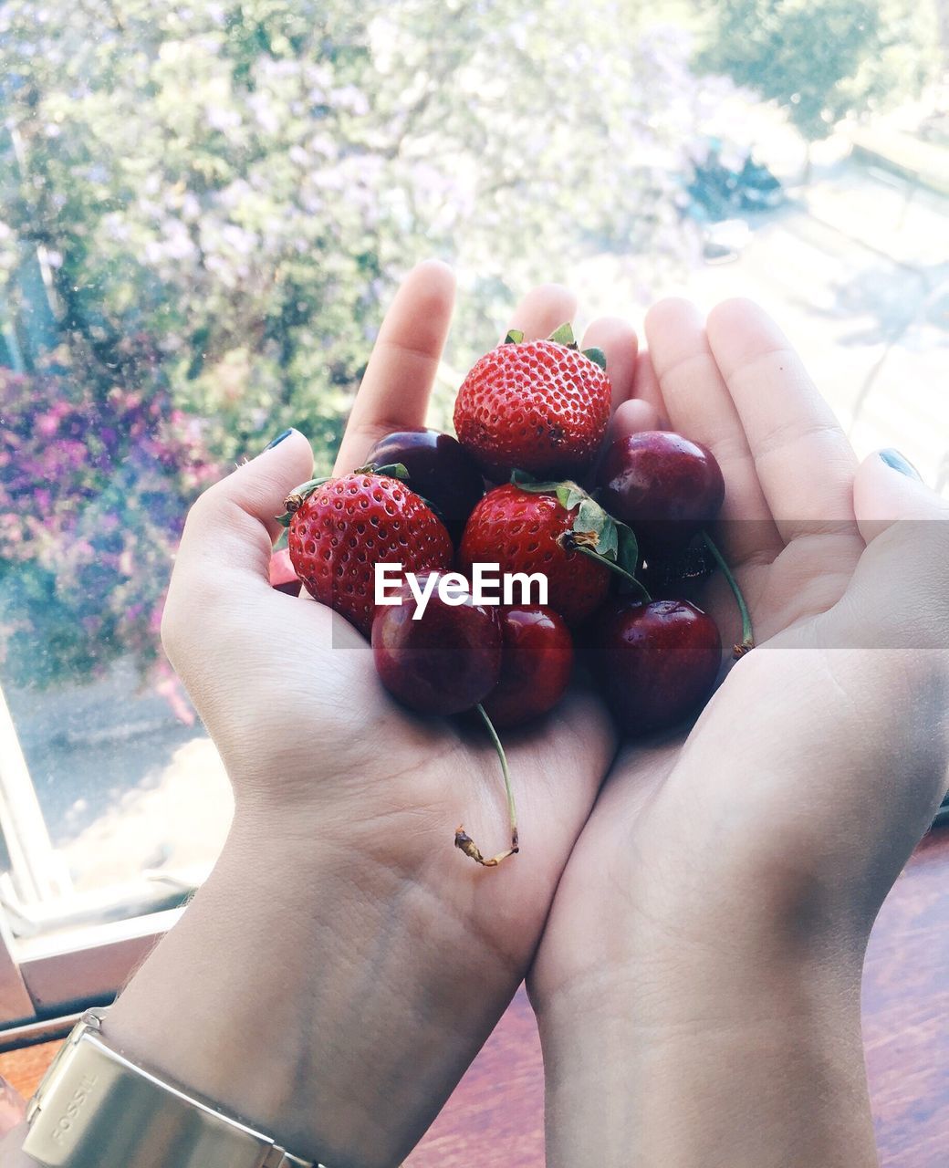 Close-up of cropped hands holding strawberries and cherries at home