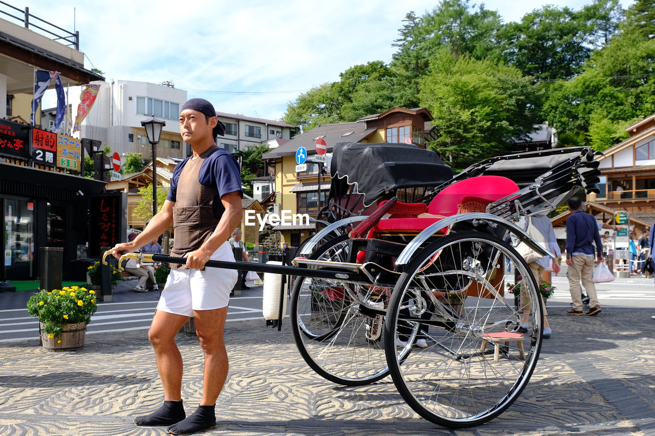 FULL LENGTH OF WOMAN WITH UMBRELLA ON CITY IN BACKGROUND