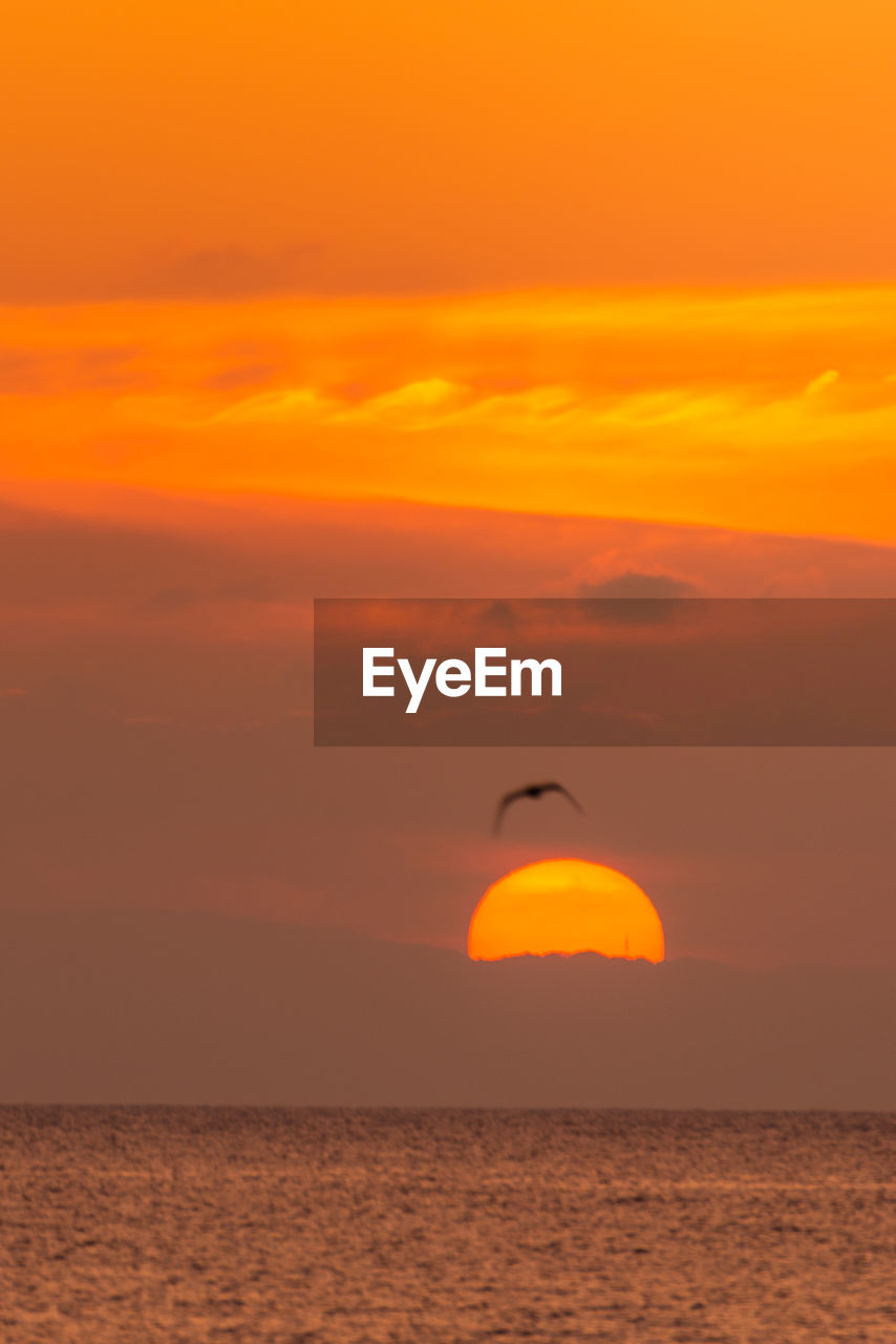 VIEW OF SEA AGAINST ORANGE SKY