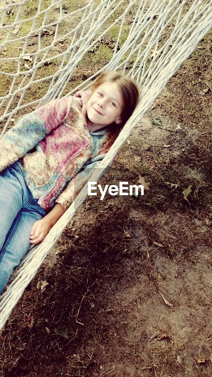 High angle portrait of girl lying on hammock at field