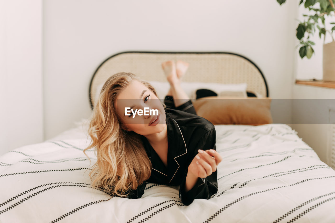 Beautiful happy smiling girl enjoying and having breakfast in bed in the morning in a cozy home