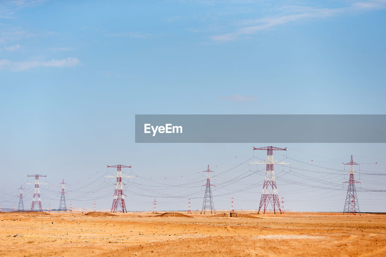 ELECTRICITY PYLON ON FIELD AGAINST BLUE SKY